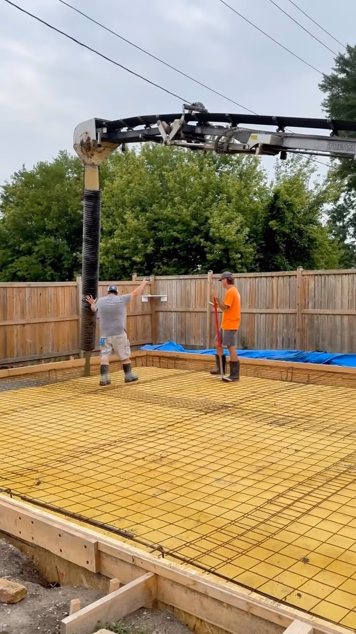 Crew placing concrete with a boom pump over a rebar-reinforced slab